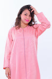 Woman wearing a pink embroidered kaftan dress with subtle swirl patterns on white background