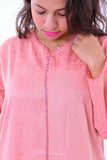Woman wearing a pink embroidered kaftan with swirl patterns and lace trim