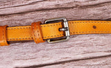 Close-up of tanned leather handbag strap with metal buckle on wooden background