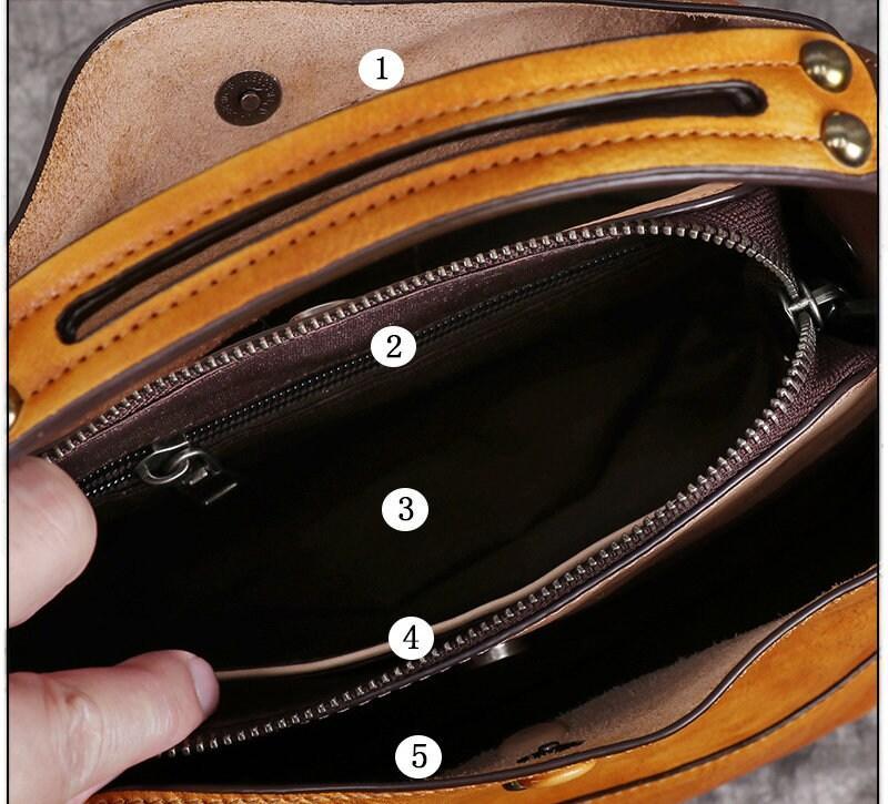 Interior view of a tanned leather crossbody handbag with multiple compartments and zipper pockets