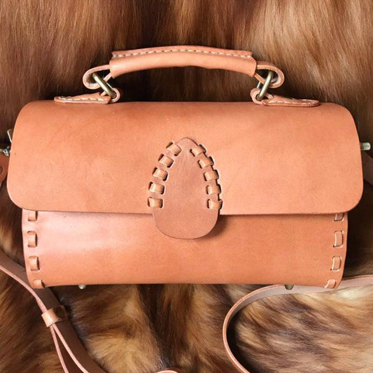 Handcrafted leather shoulder bag with top handle and stitched detailing, on brown fur background