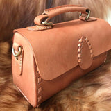 Handcrafted tan leather shoulder bag with top handle, visible stitching, and brass hardware.
