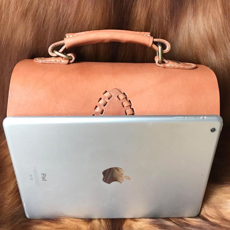 Handcrafted tan leather shoulder bag with top handle and stitched detail, shown with iPad for size reference.