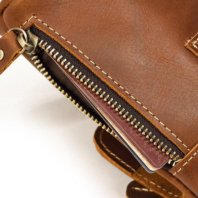Close-up of a brown full grain leather crossbody bag with zipper pouch showing cards inside