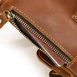 Close-up of a brown full grain leather crossbody bag with zipper pouch showing cards inside