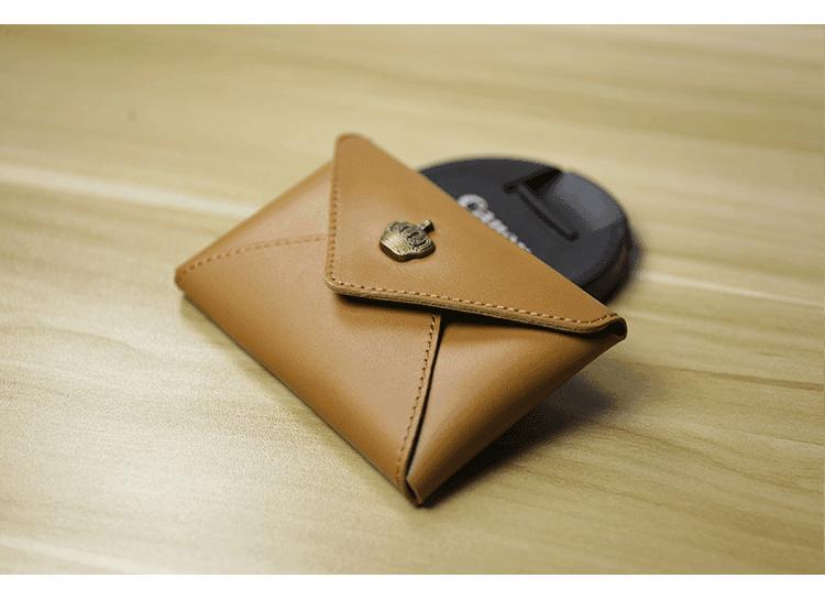 Handcrafted minimalist tan leather slim wallet with button closure on wooden table