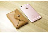 Minimalist tan leather slim wallet with clasp next to a rose gold smartphone on a wooden surface