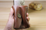 Hand holding a minimalist brown leather slim wallet with floral metal button clasp