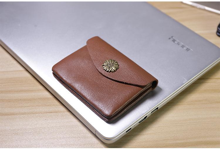 Handcrafted brown leather minimalist slim wallet with floral clasp on a laptop