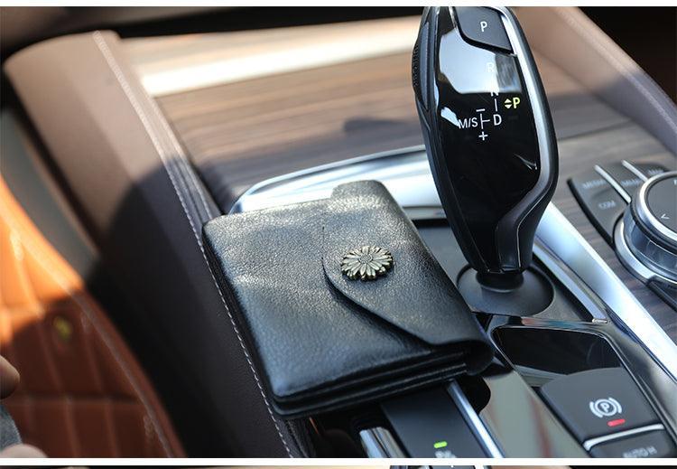 Black minimalist leather slim wallet with flower clasp on car center console
