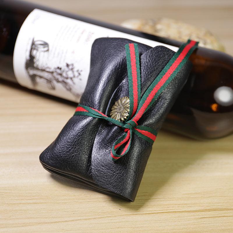 Handcrafted minimalist black leather slim wallet with red and green ribbon on wooden table