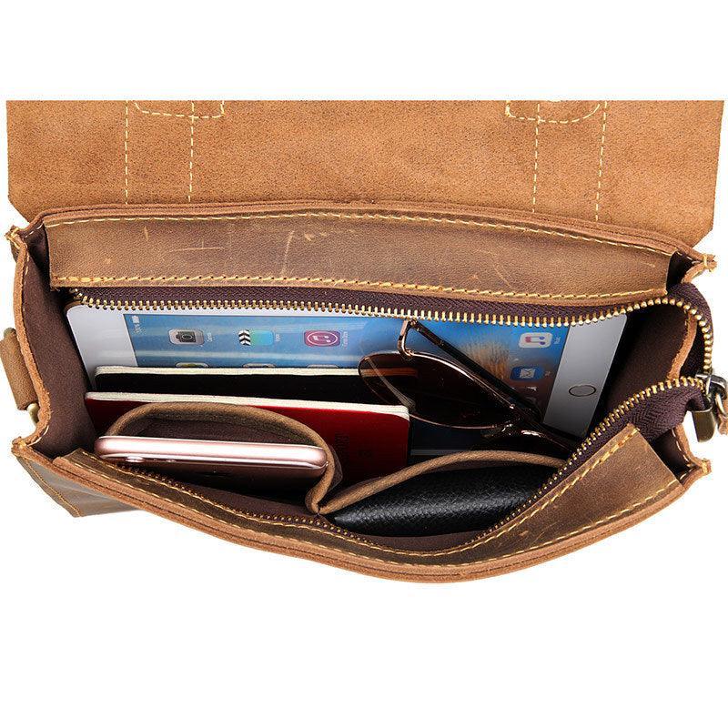 Open brown leather shoulder bag with phone, tablet, sunglasses, and wallet inside compartments