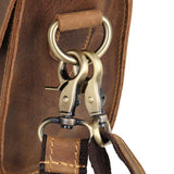 Close-up of vintage style brown leather shoulder bag with brass hardware and stitched strap