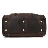 Bottom view of dark brown full grain leather duffle bag with metal feet and white stitching