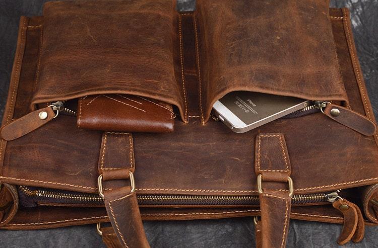 Handmade full grain leather messenger bag with front pockets, holding a wallet and smartphone
