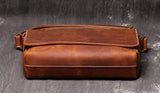 Handcrafted brown cowhide leather shoulder bag with contrast stitching on dark background