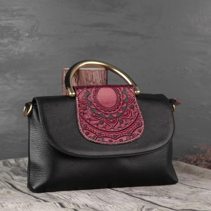Black leather handbag with engraved red flap and gold handle, on wooden surface