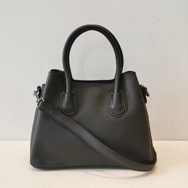 Black leather handbag with top handles and detachable shoulder strap on white background