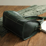 Large green cowhide leather handbag with contrast stitching on wooden surface
