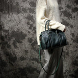 Large black cowhide leather handbag with shoulder strap, showcased by a person in neutral clothing.