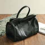 Large black cowhide leather handbag with double handles on wooden table