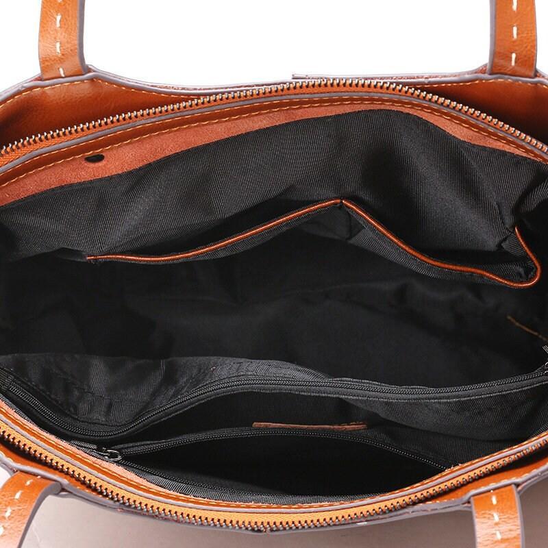 Interior view of a brown leather tote bag with black fabric lining and zipper pockets