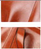 Close-up of smooth brown genuine leather tote bag with visible stitching and handle detail