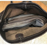 Interior of black leather bucket bag with zippered fabric compartment and stitched lining