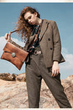 Woman outdoors holding large handcrafted brown leather clutch bag with shoulder strap