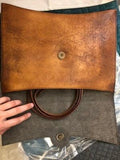 Handcrafted large leather clutch bag open to show brown handles and magnetic closure