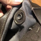 Close-up of snap button closure with stitching detail on a leather tote bag interior