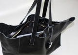 Black full grain leather tote bag with zipper pocket and double straps on white background