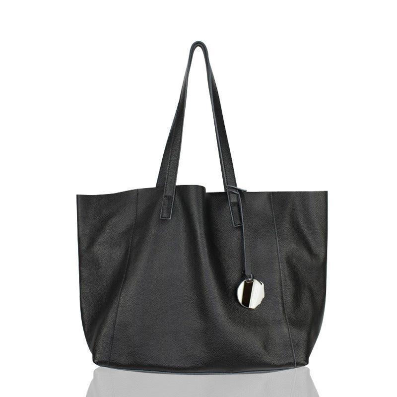 Black full grain leather tote bag with double handles and hanging keychain on white background