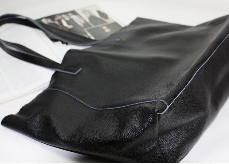 Black full-grain leather tote bag with double handles on a light background