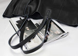 Black full grain leather tote bag with long straps, open on top of a fashion magazine