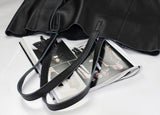Black full grain leather tote bag with long straps, open on top of a fashion magazine
