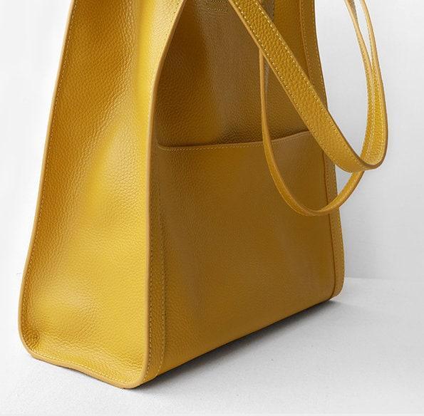 Yellow grain cowhide leather tote bag with shoulder straps on white background