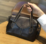 Minimalist black leather handbag with dual handles on a wooden table