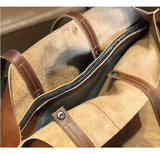 Closeup of open tan leather tote bag with brown leather handles and zipper closure