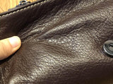 Close-up of brown genuine leather crossbody bag with magnetic snap closure