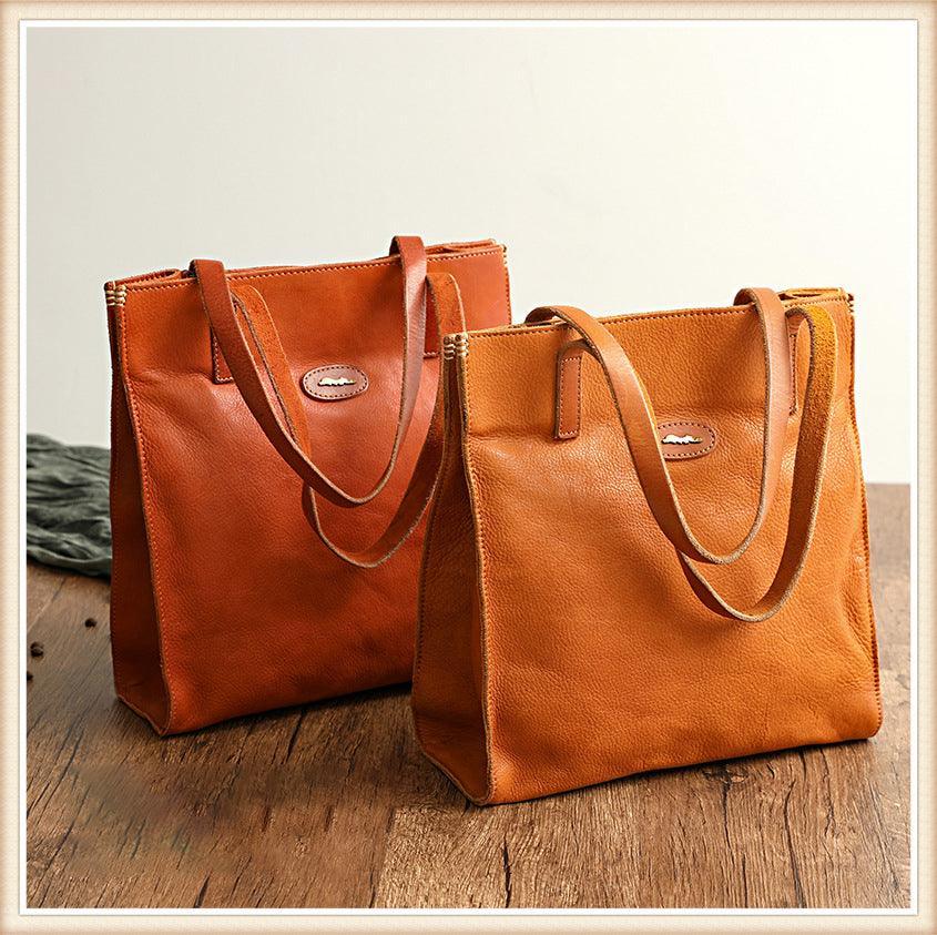 Two natural cowhide leather tote handbags with shoulder straps on wooden surface