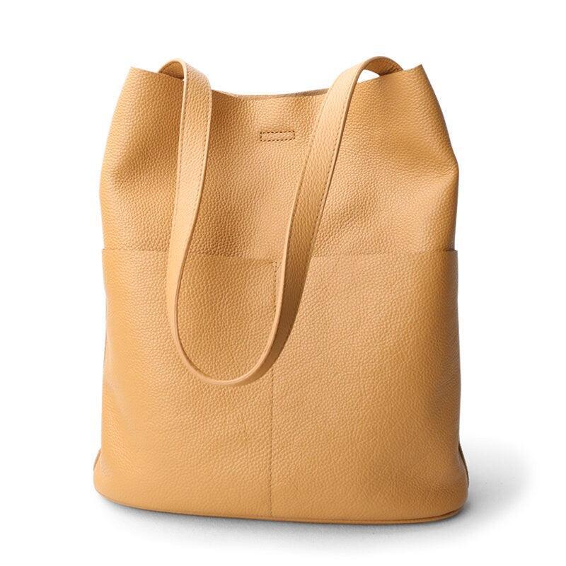 Tan cowhide leather tote bag with two front pockets and shoulder straps on white background