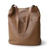 Brown cowhide leather tote bag with two front pockets and long shoulder straps.