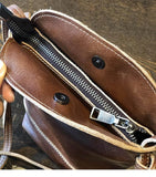 Close-up of small brown genuine leather shoulder bag with zipper and snap closure