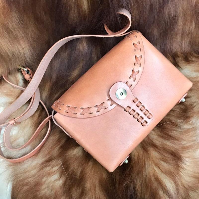 Handcrafted tan leather shoulder bag with crossbody strap and woven stitching detail on fur