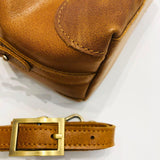 Close-up of brown vintage leather crossbody bag with gold buckle and visible stitching