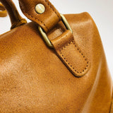Close-up of tan vintage leather Boston bag with brass hardware and fine stitching
