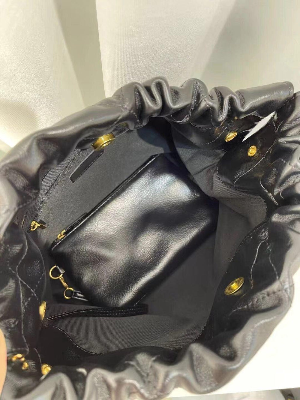 Interior of black quilted leather shoulder bag with gold-tone hardware and zip pocket