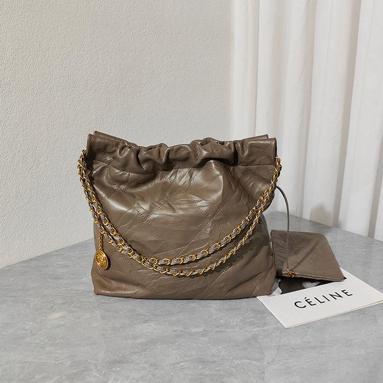 Quilted taupe leather shoulder bag with gold chain strap on marble surface, matching pouch