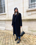 Woman in white shirt carrying black quilted leather shoulder bag with gold chain strap